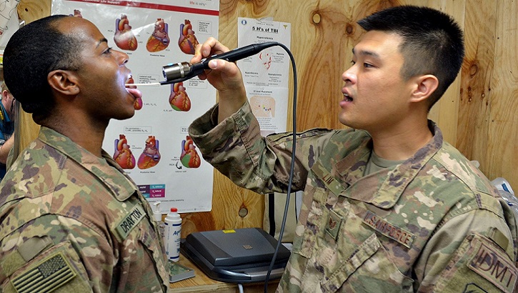Air Force Staff Sgt. Danny Lim practices conducting a throat examination on Army Sgt. Harvey Drayton at Chabelley Airfield, Djibouti. Drayton and Lim were introduced to the Telehealth In A Bag system during a recent visit that included personnel from Regional Health Command Europe's virtual health team. (U.S. Army photo by Russell Toof)