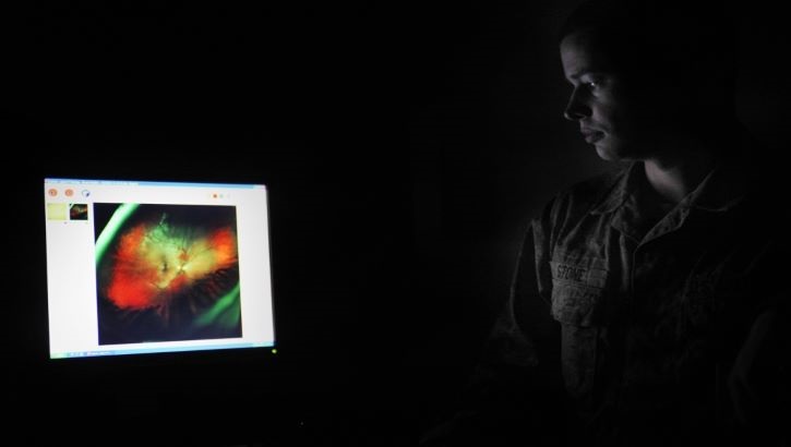 Image of Military health personnel examining a picture of an eye. Click to open a larger version of the image.