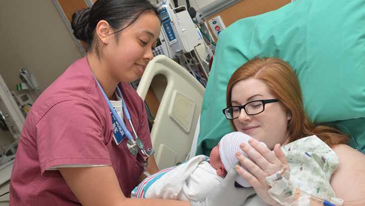 Image of Nurse hands mom her newborn baby. Click to open a larger version of the image.