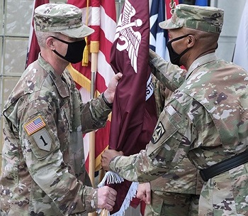 Two soldiers, wearing masks, passing a flag