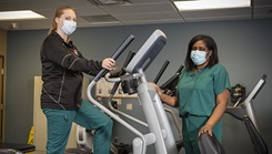 Two military personnel wearing face mask standing on gym equipment