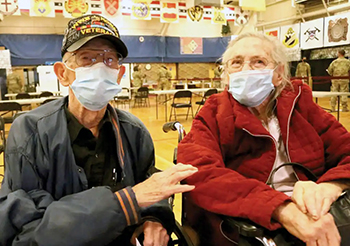 Retired veteran and his wife wearing face mask waiting to receive the COVID-19 vaccine