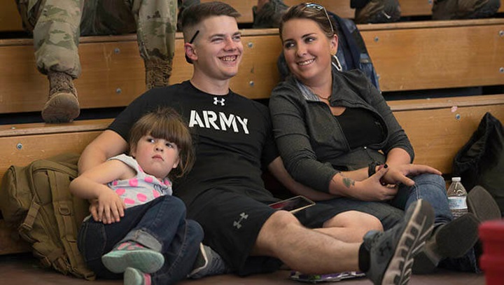 Image of Soldier sitting in gym with wife and daughter.