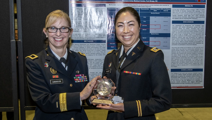 U.S. Army Brig. Gen. Katherine Simonson presents U.S. Army Capt. Stephanie Bulder with a trophy for winning the DHA Clinical Investigations Program second annual Young Investigator Competition at the 2023 annual meeting of AMSUS, the Society of Federal Health Professionals. (Photo credit: Robbie Hammer, MHS Communications)