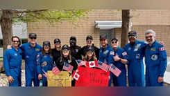 Artemis II crew members pose with U.S. Air Force Lt. Col. Danielle Anderson, center, holding a red welcome sign, and medical support staff at NASA’s Johnson Space Center