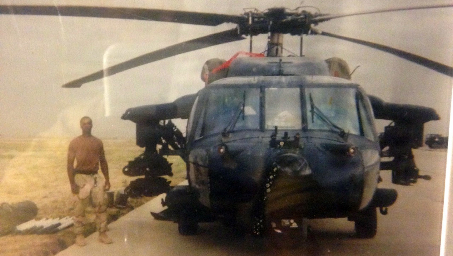 U.S. Army Veteran Clarence Davis poses beside an MH-60 Black Hawk Direct Action Penetrator 
