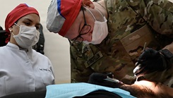 Army Maj. Loren Stringfellow, a dentist assigned to the Arkansas Army National Guard's medical detachment, works alongside Jazmin Corvalan, a Paraguayan dentist, as he extracts a patient's tooth