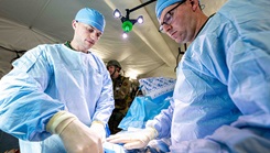 U.S. Navy Lt. Michael Fisher, general surgeon, right, and Lt. Commander Mat Bowers, orthopedic surgeon, both assigned to the 3rd Medical Battalion, 3rd Marine Logistics Group, simulates treating abdominal injury during a U.S. Air Force led operational exercise Beverley Midnight 26