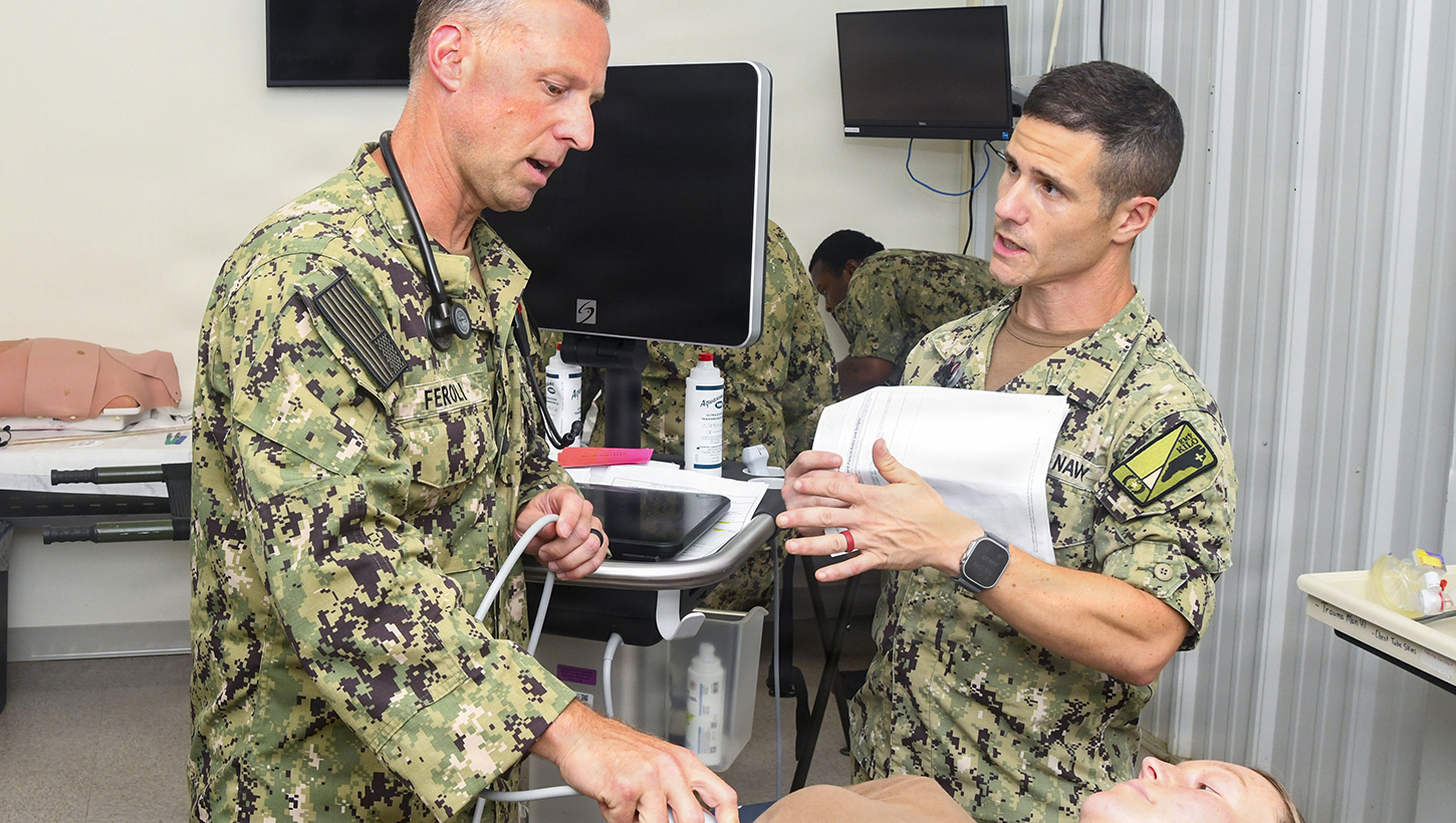 Lieutenant Commander Michael Feroli, left, assigned to Expeditionary Medical Facility Kilo, performs an abdominal ultrasound on a simulated casualty during a training