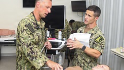 Lieutenant Commander Michael Feroli, left, assigned to Expeditionary Medical Facility Kilo, performs an abdominal ultrasound on a simulated casualty during a training