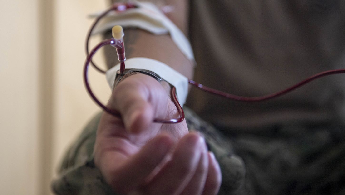 U.S. Navy Hospital Corpsman 1st Class Eric Adams, from Wildomar, California, performs a blood transfusion in a hangar bay