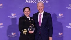 Capt. Elizabeth Adriano (left), director of Naval Medical Center San Diego, receives the 2026 Federal Health Care Executive Award for Excellence from Dr. Marc Boom (right), American Hospital Association (AHA) board chair