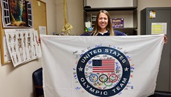 Carrie J. Belleson, a chiropractor at Naval Hospital Twentynine Palms, California, displays her United States Olympic Team flag. Belleson has been part of the medical staff for USA Olympic teams, including USA Swimming and USA Fencing, since 2019. When she is not traveling the world providing chiropractic care for Olympic athletes, Belleson spends her time treating Marines and Sailors at Naval Hospital Twentynine Palms. Marines and Sailors strive to maintain a state of readiness, which includes taking care of their musculoskeletal health. Belleson typically treats cases of spinal pain when working with active-duty service members. (Photo by Christopher C. Jones, Twentynine Palms public affairs officer).  