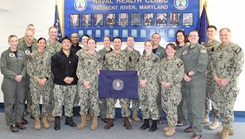 Capt. Kristin Hodapp (front row, center), Deputy Chief of the Navy Medical Service Corps (MSC), and Capt. Bryan Pyle (front row, far right), MSC Policy and Practice, pose for a group photo with MSC officers stationed across Naval Air Station Patuxent River following a "State of the Corps" address. The officers represent all three pillars of the MSC—Healthcare Administration, Clinical Care, and Research and Applied Sciences. Pictured front row, left to right: Lt. Brittany Neilson, Lt. j.g. Alisha Deschenes, Lt. Brandon Le, Lt. Natalie Grose, Lt. Matthew Sierra, Lt. Kayleigh Gutierrez, Hodapp, Cmdr. Adam Preston, and Pyle. Back row, left to right: Lt. Cmdr. Jarrett Moore, Lt. Cmdr. Matthew Christensen, Lt. Cole Engstrom, Lt. Arbi Aghali, Lt. Madeline Smith, Lt. Cmdr. Juliette Ruff, Lt. Cmdr. Danielle Whitacre, Lt. Cmdr. Kyle Shepard, Lt. Cmdr. Hadley Sulpizio, and Lt. Chase Cribbs