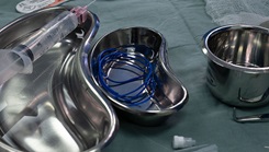 A makeshift alternative to vessel loops, created from sterile surgical gloves, rests in a surgical tray during an arteriovenous fistula surgery procedure 