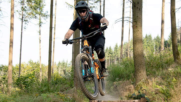 A mountain biker wearing a helmet bikes through hard terrain.