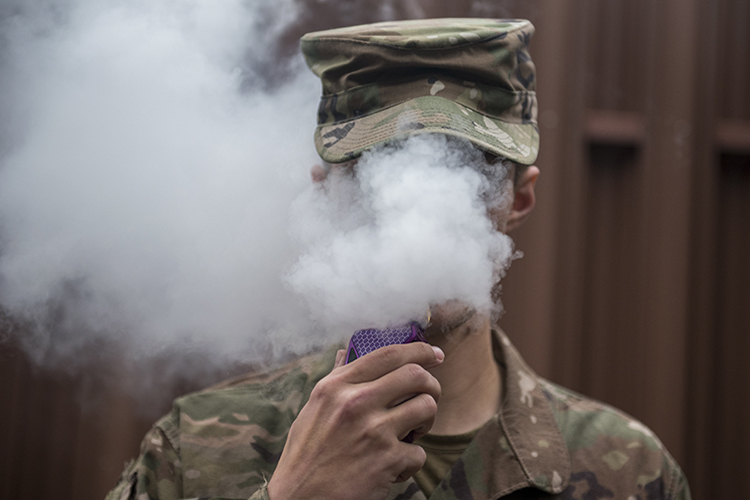 Image of A Team Offutt Airman vapes in an authorized smoking area . Click to open a larger version of the image.