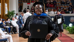 Dr. Mydirah Littlepage-Saunders holds her diploma after crossing the stage at the Uniformed Services University's 47th commencement ceremony 