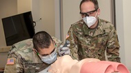 Army (then) Maj. Robert Vietor, right, watches as a Navy student practices bag-mask ventilation on an airway trainer during Transition to Clerkship airway skills training