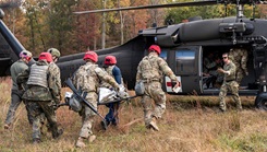 U.S. Navy Hospital Corpsman 1st Class Jonathan Shumaker, Uniformed Services University and Department of Defense’s Service Member of the Year, signals to an incoming medical team carrying a patient to a medevac helicopter during the university’s annual Bushmaster exercise