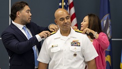 Rear Adm. Reginald “Reg” S. Ewing III, director of the Defense Health Network National Capital Region, looks on as he receives his new shoulder boards from his wife, Mina, and son Kendall, during a promotion ceremony at the USO on Naval Support Activity Bethesda. (Photo By Ricardo Reyes-Guevara)