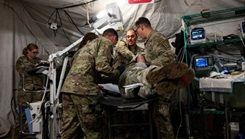 U.S. Army medics and medical officers with the 512th Field Hospital treat a role player patient inside an emergency room field tent during a mass casualty exercise