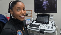 Hospital Corpsman 2nd Class Arlesha Cooper-Revish poses for a photo in front of an ultrasound machine