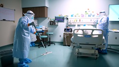 A medical professional from the Center for Sustainment of Trauma and Readiness Skills (C-STARS) Omaha, in full personal protective equipment, mops the floor while another team member tends to a simulated patient