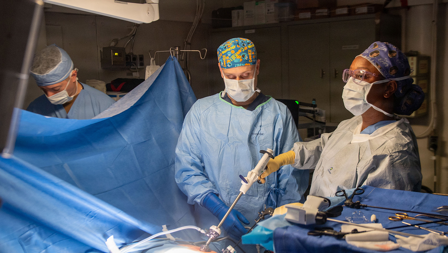 U.S. Navy Hospital Corpsman 3rd Class Nicholas Muller, centers, assists Lt. Cmdr. Carina Felix, Ship's surgeon, while performing surgery