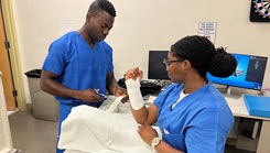 Lt. j.g. Karl Cormier, left, an occupational therapist assigned to U.S. Naval Hospital (USNH) Guam, trains Hospital Corpsman 2nd Class Alexis Hawkins on splinting techniques.