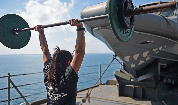 Damage Controlman 2nd Class Evelyn Medina lifts weights during a workout session on the boat deck of the amphibious dock landing ship USS Ashland. 