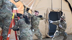 U.S. Air Force 1st Lt. Samuel Houpt, left, 8th Healthcare Operations Squadron medical service core officer, and U.S. Air Force Staff Sgt. Kemosi Hatten, 8th Medical Group personnel reliability program noncommissioned officer in charge, lift a medical tent into position during an expeditionary medical support health response team training