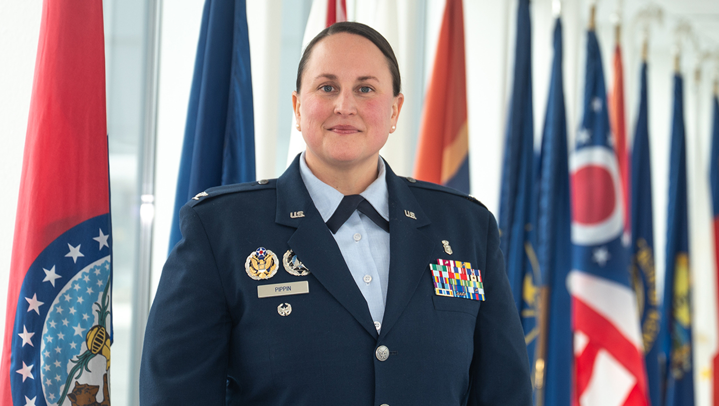 U.S. Air Force Col. Elisha Pippin, director of psychological health, poses among state flags