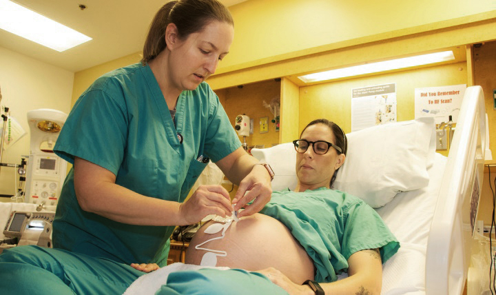 Army Maj. Lena Fabian (left), staff midwife, William Beaumont Army Medical Center in Fort Bliss, Texas, places a wireless monitoring system on Capt. Merry Fontenot, a staff midwife 36 weeks into her pregnancy. (Photo by Marcy Sanchez, William Beaumont Army Medical Center Public Affairs Office)