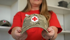 Jessica Pfeffer holding a military style hat with the Red Cross emblem