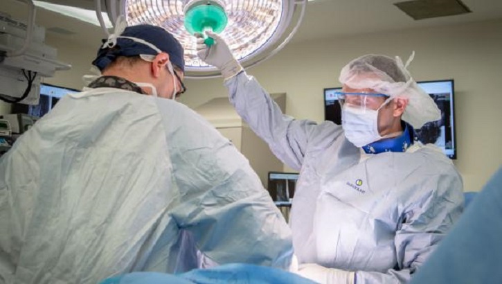 Image of Two medical military personnel in an operating room. Click to open a larger version of the image.