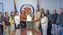 Member of the U.S. Naval Hospital Yokosuka Clinical Quality Management Department pose with Capt. Donavon YapShing, deputy director of U.S. Naval Hospital Yokosuka and executive officer of U.S. Navy Medicine Readiness and Training Command Yokosuka, and a Joint Commission accreditation certificate.