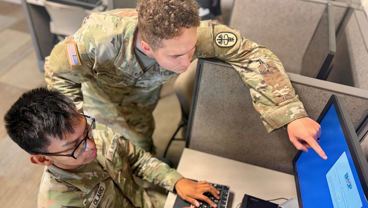 Two services members working at the computer