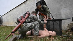 Lt. Simon Choi, Assistant Service Chief for the Medical Intensive Care Unit, at Walter Reed National Military Medicine Center (WRNMMC), right, and Hospital Corpsman 3rd Class Evan Selinger, left, assigned both to Navy Medical Readiness and Training Command (NMRTC) Bethesda, provide emergency care as part of the Tactical Combat Casualty Care course testing. 