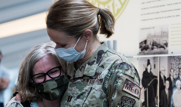 Image of Military health personnel wearing face masks hugging.