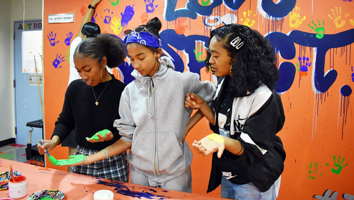 Midori Robinson, Kyleigh Rose and Keisha McNeill paint their hands so they can put a handprint on the “Love is Respect” mural during the Camp Zama Youth Center Teen Dating Violence Awareness Lock-In at Camp Zama. (U.S. Army photo by Winifred Brown)