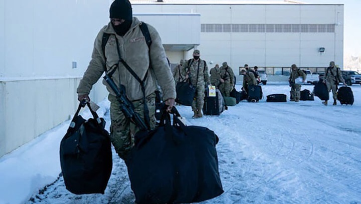 Image of Airman in winter gear carry deployment gear at Joint Base Elmendorf Richardson, Alaska in preparation for Operation Polar Force exercise.