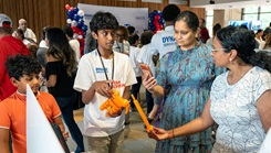 A STEM Achiever demonstrates a 3D-printed assistive device for families at the STEM Fair