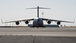 A U.S. Air Force C-17 Globemaster III is marshalled on a flight line.