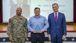 Jose Rodriguez, center, with Navy Medicine Readiness and Logistics Command, is presented the Civilian Medical Logistician of the Year Award by Dr. Michael McGinnis, Bureau of Medicine and Surgery (BUMED) executive director, during the 2026 Medical Logistics Symposium