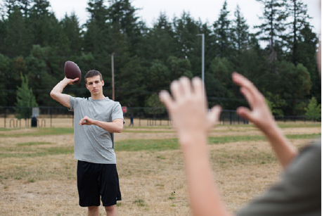 Teen boy throws a football to a friends hands