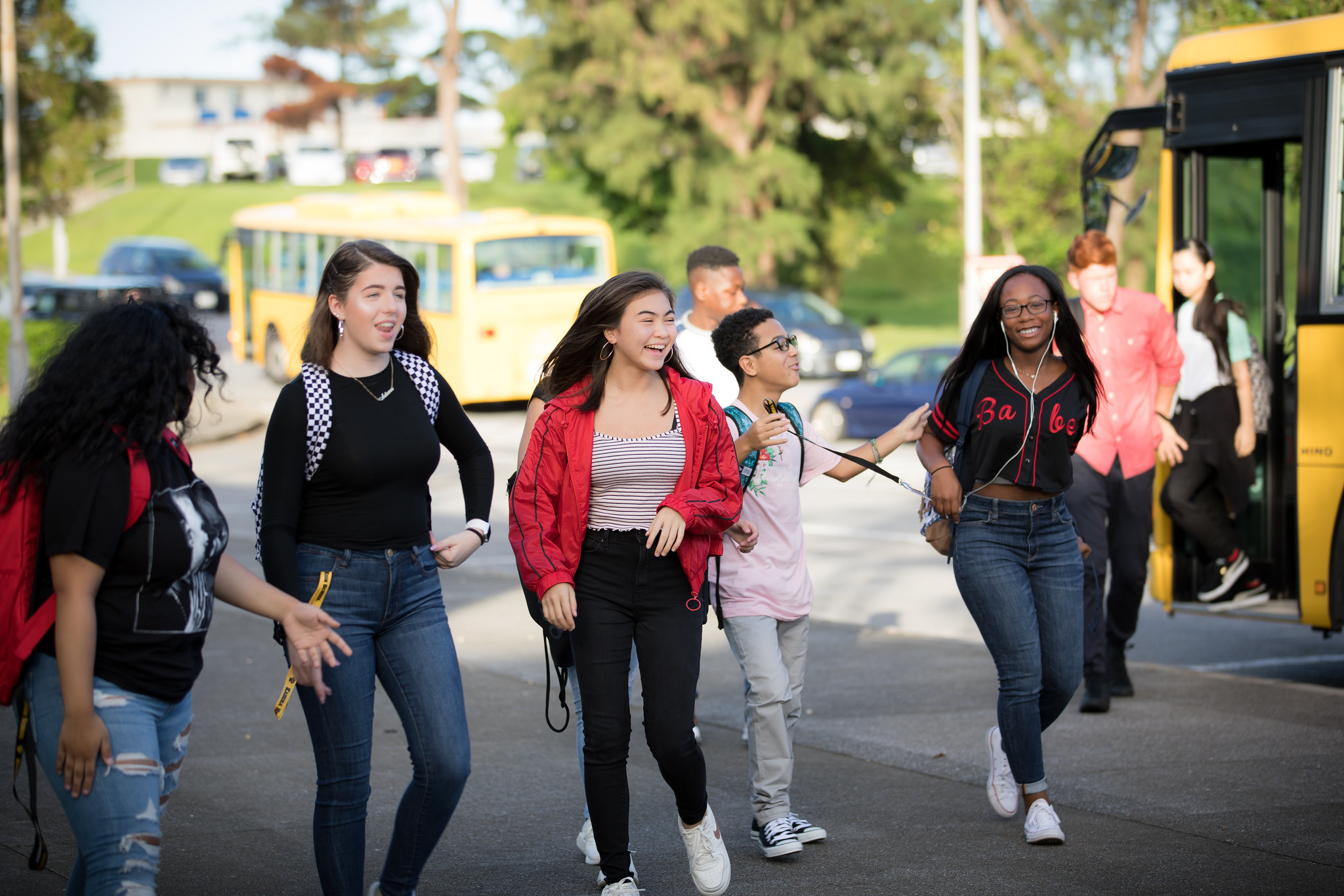 group of teenagers laughing together as they arrive at school